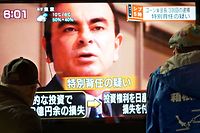 This picture taken on December 21, 2018 shows pedestrians looking at a television news programme featuring former Nissan chief Carlos Ghosn, in Tokyo. - Former Nissan boss Carlos Ghosn will be spending the beginning of 2019 behind bars after a Tokyo court on December 31 extended his detention through to January 11, local media reported. (Photo by Kazuhiro NOGI / AFP)