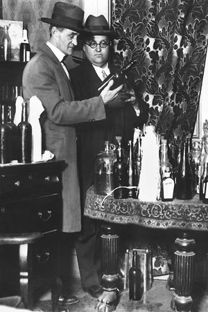 Polizisten prüfen sichergestellte Flaschen mit Alkohol, aufgenommen während einer Razzia in einer illegalen Kneipe.