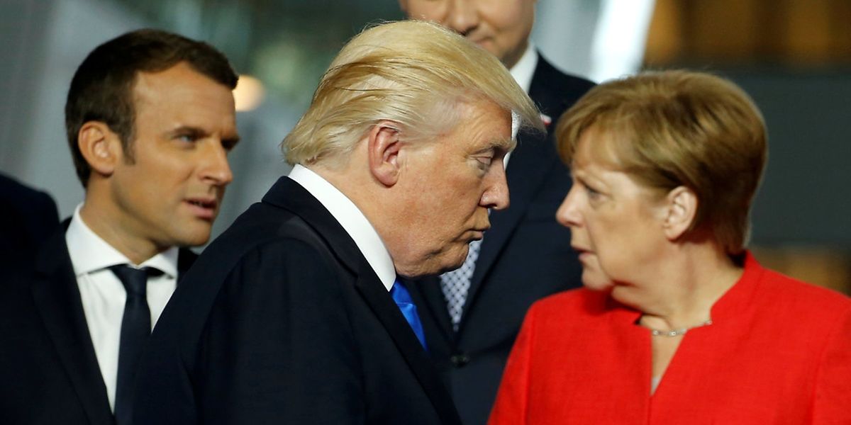 U.S. President Donald Trump (C) walks past French President Emmanuel Macron (L) and German Chancellor Angela Merkel on his way to his spot for a family photo during the NATO summit at their new headquarters in Brussels, Belgium May 25, 2017.  REUTERS/Jonathan Ernst