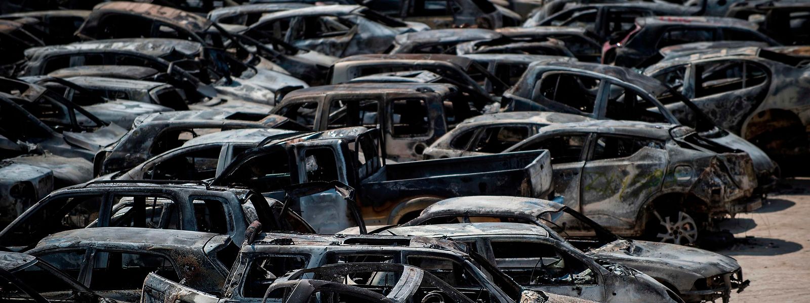 Völlig ausgebrannte Fahrzeuge auf dem Parkplatz eines Fußballstadions.