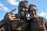 With mud coated heavy metal fans pose for a picture during the Wacken Open Air heavy metal festival in Wacken, northern Germany, on August 5, 2016. / AFP PHOTO / dpa / Axel Heimken / Germany OUT