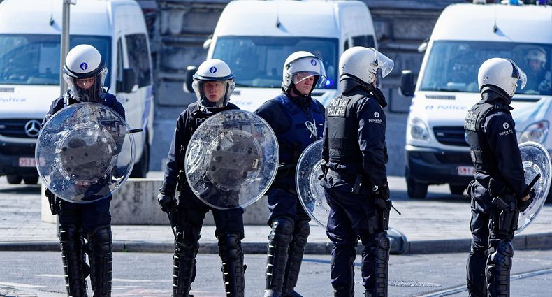 Belgian police offiers wearing protective gears stand at the site of unrests in Anderlecht, Brussels, on April 11, 2020. - People gather in a reaction to the death of a 19-year-old young man, who died after his scooter collided with a police car during a chase the night before. (Photo by OLIVIER GOUALLEC / various sources / AFP) / Belgium OUT