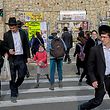 People cross a street in an ultra-Orthodox Jewish neighbourhood in Jerusalem, on March 11, 2021. - Tensions between mainstream Israelis and ultra-Orthodox Jews, or haredim, have roiled throughout the COVID-19 pandemic. Refusals by top rabbis to close religious schools and street-packing haredi funerals that ignored restrictions on gatherings infuriated the public, which blamed haredi defiance for extended lockdowns. But beyond hostilities, experts said the pandemic has also ignited an internal debate within the ultra-Orthodox community over whether its conduct during the crisis was justified. (Photo by MENAHEM KAHANA / AFP)