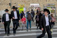 People cross a street in an ultra-Orthodox Jewish neighbourhood in Jerusalem, on March 11, 2021. - Tensions between mainstream Israelis and ultra-Orthodox Jews, or haredim, have roiled throughout the COVID-19 pandemic. Refusals by top rabbis to close religious schools and street-packing haredi funerals that ignored restrictions on gatherings infuriated the public, which blamed haredi defiance for extended lockdowns. But beyond hostilities, experts said the pandemic has also ignited an internal debate within the ultra-Orthodox community over whether its conduct during the crisis was justified. (Photo by MENAHEM KAHANA / AFP)