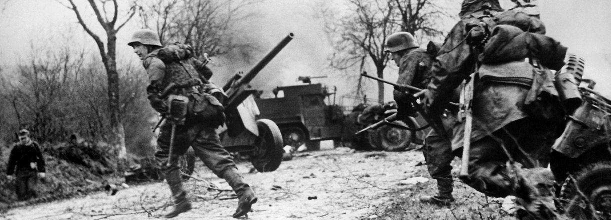 (FILES) This file photograph taken on December 16, 1944,  from a captured German's film, provided on December 27, 1944, shows German infantrymen crossing a road somewhere on the western Front during their drive into the US lines during The Battle of The Bulge - The Ardennes Counteroffensive, in western Belgium. - The Battle of the Bulge was the last German offensive of World War II, and the Siege of Bastogne the scene of a heroic defence by US paratroopers. Seventy-five years later the Belgian town is hosting a weekend of colourful re-enactments followed by solemn ceremonies of remembrance. Veterans, historians and military enthusiasts will join international officials to mark the now legendary close quarters battle on a snowbound wooded plateau. Bastogne's relief in late December 1944 by General George "Old Blood and Guts" Patton helped seal his reputation as one of America's military giants. (Photo by STR / OWI / AFP)