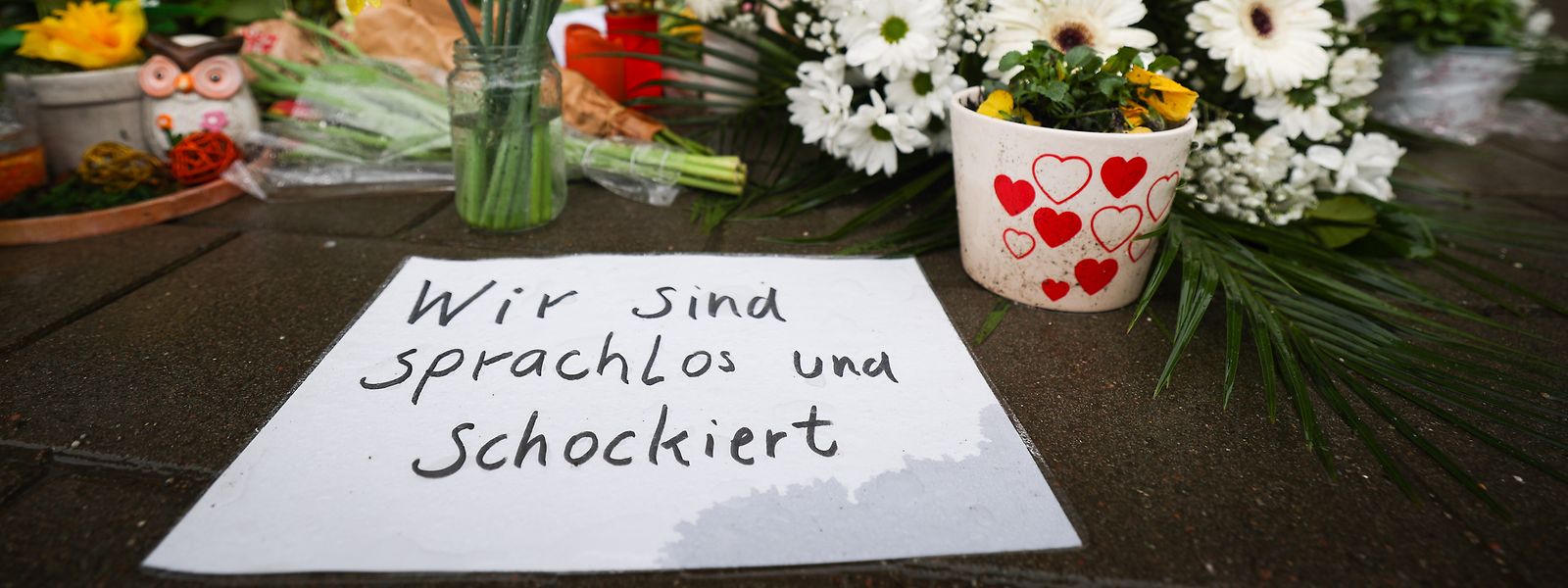 Ein Zettel mit dem Text „Wir sind sprachlos und schockiert“ liegt neben Blumen und Kerzen vor dem Eingangsbereich des Gemeindehauses der Zeugen Jehovas in Hamburg. 