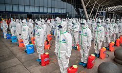 TOPSHOT - Staff members line up at attention as they prepare to spray disinfectant at Wuhan Railway Station in Wuhan in China's central Hubei province on March 24, 2020. - China announced on March 24 that a lockdown would be lifted on more than 50 million people in central Hubei province where the COVID-19 coronavirus first emerged late last year. (Photo by STR / AFP) / China OUT