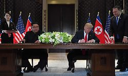 US President Donald Trump (2nd R) and North Korea's leader Kim Jong Un (2nd L) sign documents as US Secretary of State Mike Pompeo (R) and the North Korean leader's sister Kim Yo Jong (L) look on at a signing ceremony during their historic US-North Korea summit, at the Capella Hotel on Sentosa island in Singapore on June 12, 2018.

Donald Trump and Kim Jong Un became on June 12 the first sitting US and North Korean leaders to meet, shake hands and negotiate to end a decades-old nuclear stand-off. / AFP PHOTO / SAUL LOEB