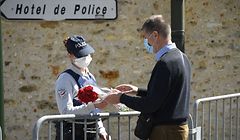 A man hands flowers to police officers to be taken down to the police station where a police official was stabbed death Friday in Rambouillet, south-west of Paris, on April 25, 2021. - French prosectors opened a terror probe after a woman working for the police was stabbed to death in Rambouillet, a well-heeled usually peaceful commuter town about 60 kilometres (40 miles) from Paris. The attack revived the trauma of a spate of deadly attacks last year in France blamed on Islamist radicals. (Photo by Bertrand GUAY / AFP)