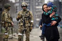 Imagem de uma residente de Mariupol caminhando com o filho sob o olhar das tropas russas.