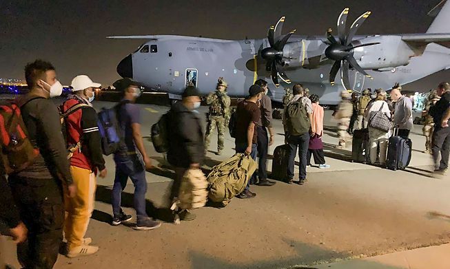 French and Afghan nationals lining up to board a French military transport plane at the Kabul airport on August 17