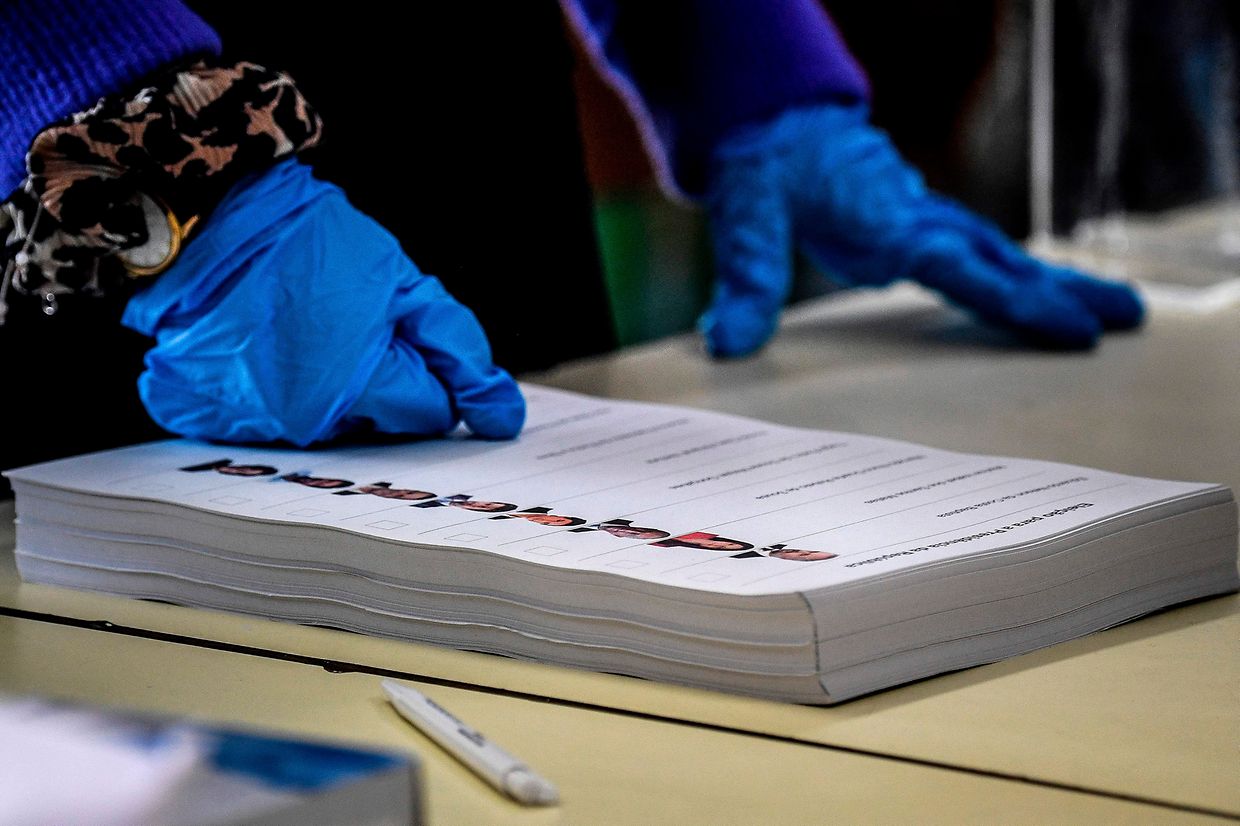 Um elemento de uma mesa de voto em Telheiras, Lisboa, utiliza luvas para manobrar os boletins de voto.