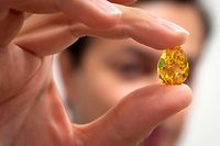 Rahul Kadakia, senior vice president and head of the Jewelry Department at Christie's Auction house, holds up 'The Orange' diamond during a media preview in New York, October 11, 2013. 'The Orange' is the largest fancy vivid orange diamond known to exist with a  carat weight of 14.82 carats and is expected to fetch up to $20 Million USD at auction November 12 in Geneva.    REUTERS/Carlo Allegri  (UNITED STATES - Tags: BUSINESS SOCIETY)