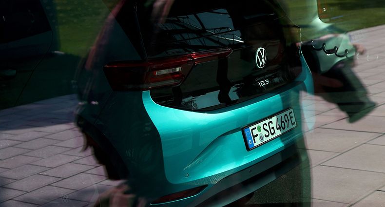 A new Volkswagen (VW) ID.3 electric car is connected to a charging cable behind a shop window at the headquarters of German carmaker Volkswagen (VW) in Wolfsburg, northern Germany on March 26, 2021. - German auto giant Volkswagen said it is aiming to dominate the electric car market by 2025 as it accelerates the pace to catch up with US pioneer Tesla. Volkswagen sold 422,000 electrified vehicles in 2020. Of those, 230,000 were fully electric cars -- or three times more than in 2019 -- and the remainder petrol-electric hybrids. (Photo by Ronny Hartmann / AFP)