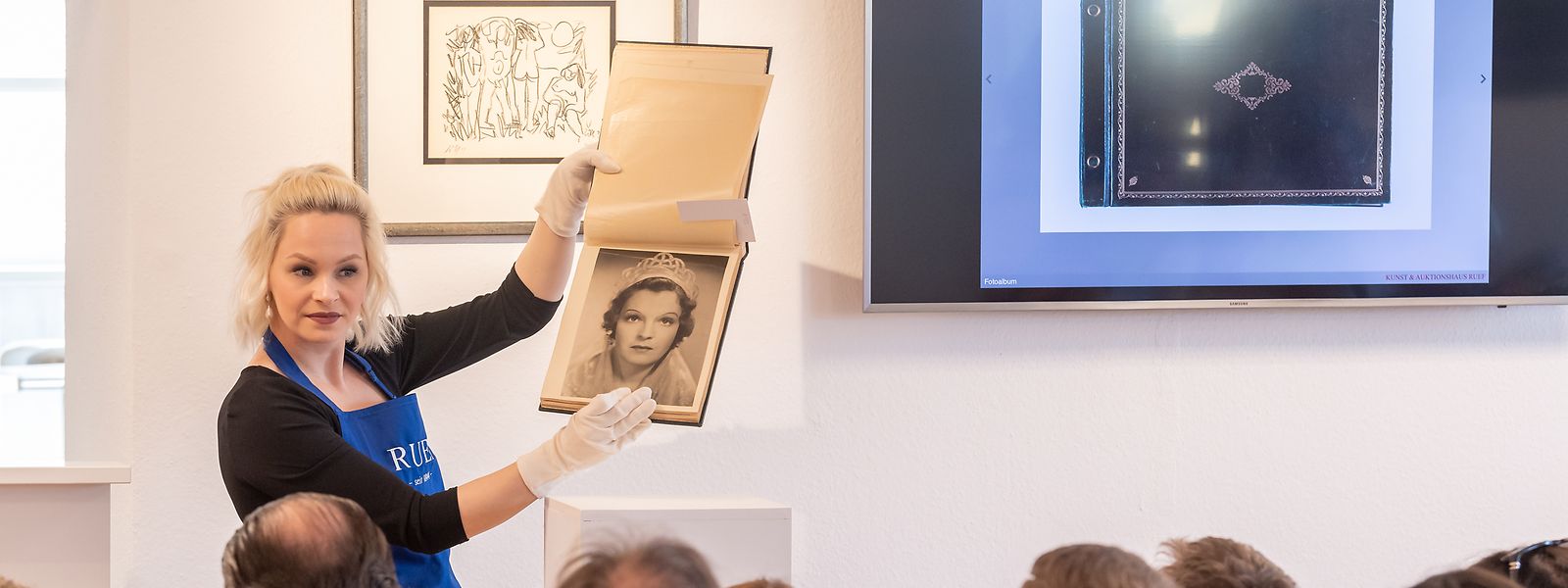 Auktionshaus-Besucher nehmen an einer Versteigerung von Romy-Schneider-Devotionalien teil. Auf dem Foto ist ein Fotoalbum mit Set-Bildern von Romy Schneiders Mutter Magda Schneider zu sehen.