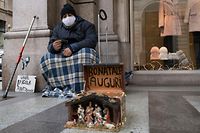 TURIN, ITALY - DECEMBER 15: A homeless person wearing a protective mask poses for a photo while wishing happy holidays on December 15, 2020 in Turin, Italy. Italy is preparing for the holiday period and while Covid-19 contagions lower, the Italian National Institute of Statistics warns of over 73,000 businesses closures, among which 13,000 are unlikely to open again due to the Covid-19 pandemic. (Photo by Stefano Guidi/Getty Images)