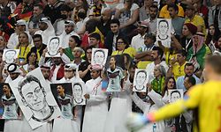 People on the stands hold portraits of German football player Mesut Ozil during the Qatar 2022 World Cup Group E football match between Spain and Germany at the Al-Bayt Stadium in Al Khor, north of Doha on November 27, 2022. (Photo by Ina Fassbender / AFP)
