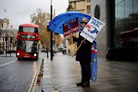 Anti-Brexiteer activist Steve Bray holds placards and an EU-themed umbrella as he stands outside a conference centre in central London on December 4, 2020, as talks continue on a trade deal between the EU and the UK. - With just a month until Britain's post-Brexit future begins and trade talks with the European Union still deadlocked, the UK government on Tuesday urged firms to prepare as it scrambles to finish essential infrastructure. (Photo by Tolga Akmen / AFP)