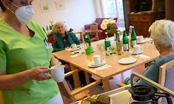 A staff offers coffe and cake for residents in the retirement home St. Barbara of German welfare organisation in Stuttgart, southern Germany, on November 17, 2020, amid the new coronavirus COVID-19 pandemic. (Photo by THOMAS KIENZLE / AFP)