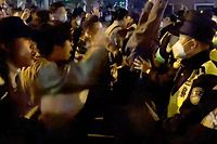 This frame grab from eyewitness video footage made available via AFPTV on November 27, 2022 shows demonstrators shouting slogans as police hold their positions, in Shanghai. - Angry crowds took to the streets in Shanghai in the early hours of November 27 and videos on social media showed protests in other cities across China, as public opposition to the government's hardline zero-Covid policy mounts. (Photo by AFPTV / AFP)