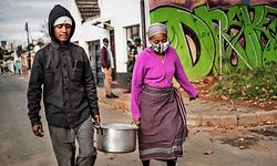 A a pot of home-cooked food is carried from a private home by volunteers for the grassroots charity, Hope for Vrededorp, en route to a daily food distribution in the impoverished district of Vrededorp in Johannesburg, on April 28, 2020. - The group home cooks almost 100 meals everyday since the beginning of South Africa lockdown, and distribute them to the needy residents of the neighbourhood. (Photo by MARCO LONGARI / AFP)