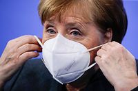 German Chancellor Angela Merkel puts on a face mask after a press conference following talks via video conference with Germany's state premiers on the extension of the current lockdown due to the coronavirus COVID-19 pandemic, at the Chancellery in Berlin on January 19, 2021. (Photo by Hannibal HANSCHKE / POOL / AFP)