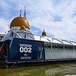 This picture taken on December 17, 2019 shows the garbage-picking Interceptor seen on the Klang river, in front of a mosque in Klang, on the outskirts of Kuala Lumpur. - Scooping waste from a Malaysian river to stop it reaching the sea, a solar-powered barge named the "Interceptor" is the latest weapon in a global battle to rid the world's waters of plastic. (Photo by Mohd RASFAN / AFP)