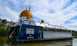 This picture taken on December 17, 2019 shows the garbage-picking Interceptor seen on the Klang river, in front of a mosque in Klang, on the outskirts of Kuala Lumpur. - Scooping waste from a Malaysian river to stop it reaching the sea, a solar-powered barge named the "Interceptor" is the latest weapon in a global battle to rid the world's waters of plastic. (Photo by Mohd RASFAN / AFP)