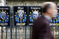 TOPSHOT - Pedestrians walk past placards featuring Britain's Prime Minister Theresa May and opposition Labour party leader Jeremy Corbyn near the Houses of Parliament in central London on April 3, 2019. - Prime Minister Theresa May was to meet on Wednesday with the leader of Britain's main opposition party in a bid to thrash out a Brexit compromise with just days to go until the deadline for leaving the bloc. (Photo by Tolga Akmen / various sources / AFP)
