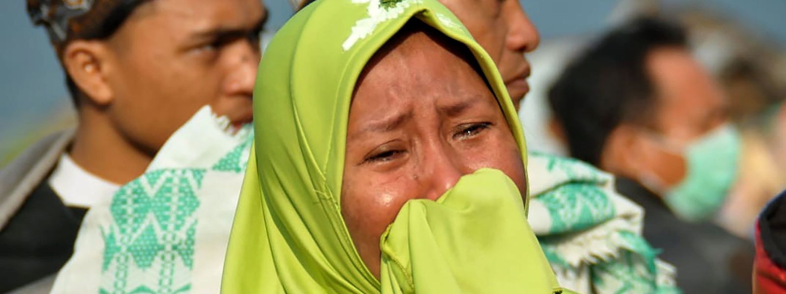 A woman cries as people look at the damages after an earthquake and a tsunami hit Palu, on Sulawesi island on September 29, 2018. - Rescuers scrambled to reach tsunami-hit central Indonesia and assess the damage after a strong quake brought down several buildings and sent locals fleeing their homes for higher ground. (Photo by MUHAMMAD RIFKI / AFP)