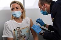 A French red cross member administers a dose of the Pfizer/BioNTech vaccine to a woman at the Covid-19 vaccination center Paris La Defense Arena in Nanterre, west of Paris on the opening day on May 3, 2021. (Photo by BERTRAND GUAY / AFP)