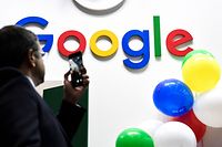 (FILES) In this file photograph taken on May 16, 2019 in Paris, a man takes a picture with his mobile phone of the logo of the US multinational technology and Internet-related services company Google as he visits the Vivatech startups and innovation fair. - France's competition regulator fined Google 220 million euros ($267 million) on June 07, 2021, after finding it had abused its dominant market position for placing online ads, the latest move by European authorities to take tougher stances against US tech giants. (Photo by ALAIN JOCARD / AFP)
