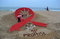 (FILES) In this file photograph taken on November 29, 2013, Indian sand artist Sudersan Pattnaik gives the final touches to a sand sculpture on the eve of World AIDS Day, as a horseman rides by on Golden Sea Beach in Puri, some 65 kms east of Bhubaneswar. - HIV-related deaths last year fell to around 770,000 -- some 33 percent lower than in 2010 -- the United Nations said July 15, 2019, but warned that global efforts to eradicate the disease were stalling as funding dries up. An estimated 37.9 million people now live with HIV -- a record 23.3 million of those have access to some antiretroviral therapy (ART), UNAIDS said in its annual report. (Photo by ASIT KUMAR / AFP)