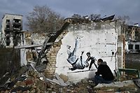 A local resident looks at a Banksy-style graffiti on the wall of a destroyed building, but its origin remains unconfirmed by the artist, in Borodyanka, near Kyiv on November 12, 2022, amid the Russian invasion of Ukraine. - Banksy, the elusive British street artist, has painted a mural on a bombed-out building outside Ukraine's capital, in what Ukrainians have hailed as a symbol of their country's invincibility. On November 11's night the world-famous graffiti artist posted on Instagram three images of the artwork -- a gymnast performing a handstand amid the ruins of a demolished building in the town of Borodyanka northwest of the Ukrainian capital Kyiv. (Photo by Genya SAVILOV / AFP) / RESTRICTED TO EDITORIAL USE - MANDATORY MENTION OF THE ARTIST UPON PUBLICATION - TO ILLUSTRATE THE EVENT AS SPECIFIED IN THE CAPTION