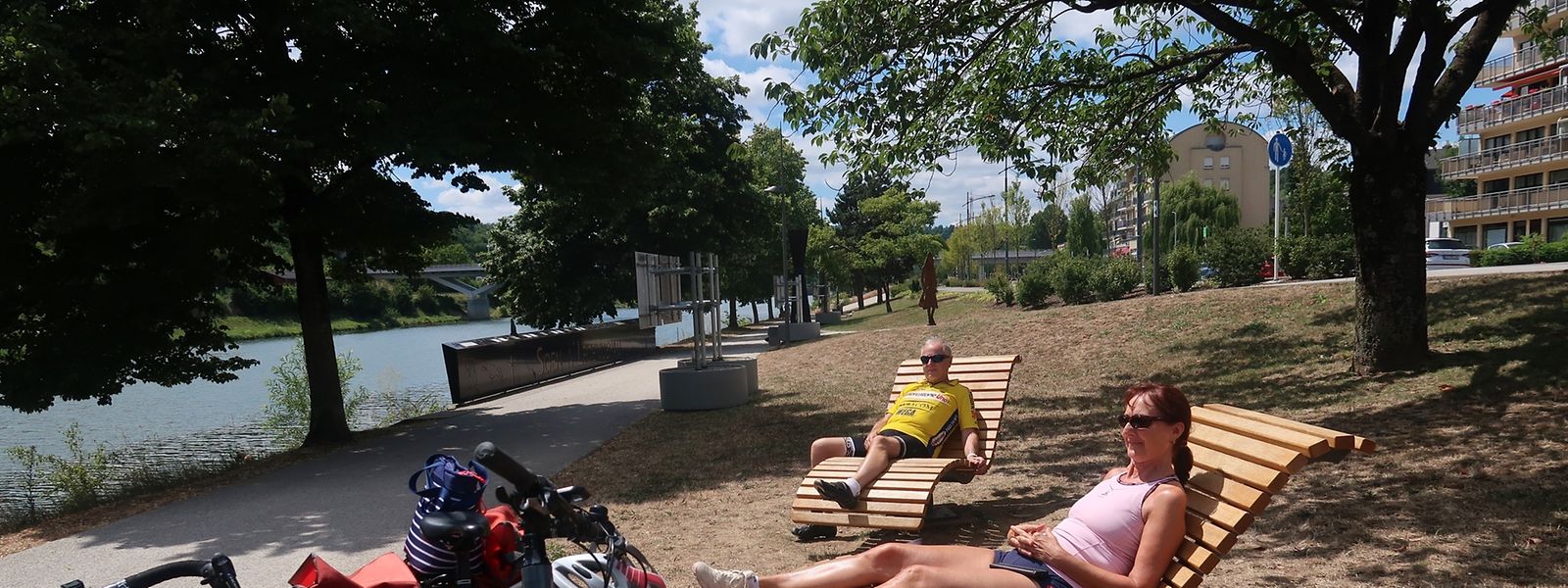 Diese Radfahrer legen eine Pause auf den hölzernen Liegestühlen ein. Im Hintergrund der Sagen- und Legendenpfad.