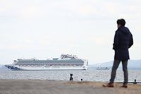 A member of the media looks out toward the Diamond Princess cruise ship (L) with over 3,000 people as it sits anchored in quarantine off the port of Yokohama on February 4, 2020, a day after it arrived with passengers feeling ill. - Japan has quarantined the cruise ship carrying 3,711 people and was testing those onboard for the new coronavirus on February 4 after a passenger who departed in Hong Kong tested positive for the virus. (Photo by Behrouz MEHRI / AFP)