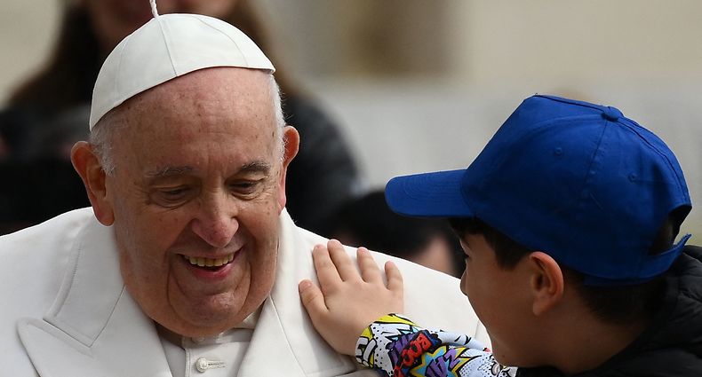 TOPSHOT - A boy pats Pope Francis on the shoulder while leaving in the popemobile car on March 29, 2023 at the end of the weekly general audience at St. Peter's square in The Vatican. (Photo by Vincenzo PINTO / AFP)