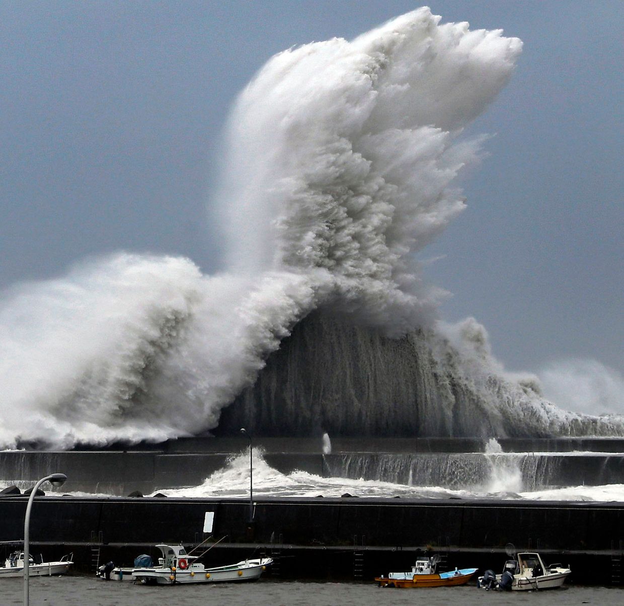 Hohe Wellen brechen an Wellenbrechern in einem Hafen von Aki.