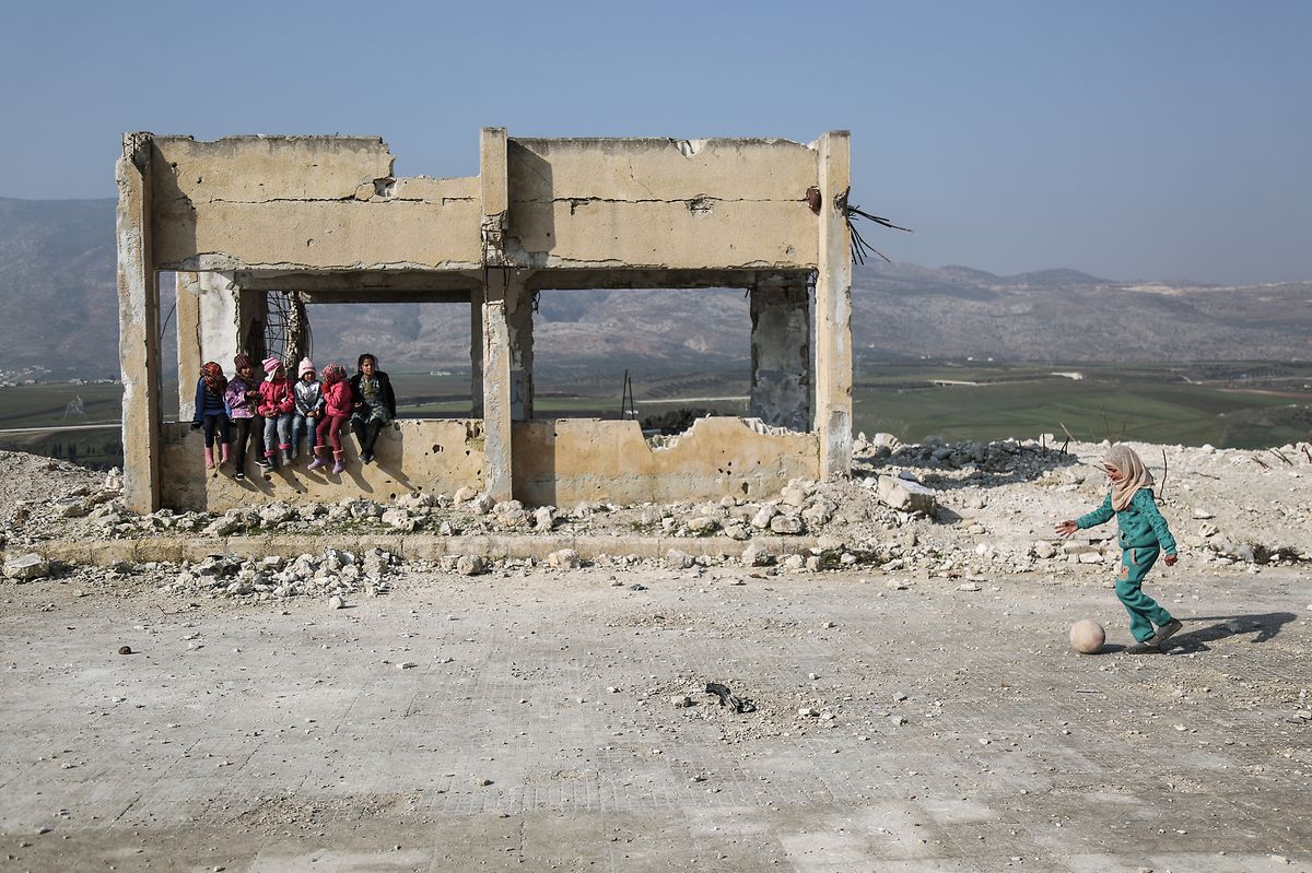 Syrien, Jisr al-Shughur: Kinder spielen in den Trümmern der schwer beschädigten Al-Kefir-Schule. Mehr als 200 Schüler gehen hier immer noch zur Schule, obwohl Angriffe der syrischen Armee hier verheerende Spuren hinterlassen haben.