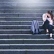 Bullying, discrimination or stress concept. Sad teenager crying in school yard. Upset young female student having anxiety. Upset victim of abuse or harassment sitting on stairs outdoors with backbag. - Bilder 