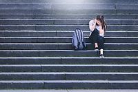 Bullying, discrimination or stress concept. Sad teenager crying in school yard. Upset young female student having anxiety. Upset victim of abuse or harassment sitting on stairs outdoors with backbag. - Bilder 