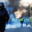 TOPSHOT - People stand as a man gestures in front of gendarmes on Caen's circular road on November 18, 2018 in Caen, northwestern France, on a second day of action after a nationwide popular initiated day of protest called "yellow vest" (Gilets Jaunes in French) movement against high fuel prices which has mushroomed into a widespread protest against stagnant spending power under French President. (Photo by CHARLY TRIBALLEAU / AFP)