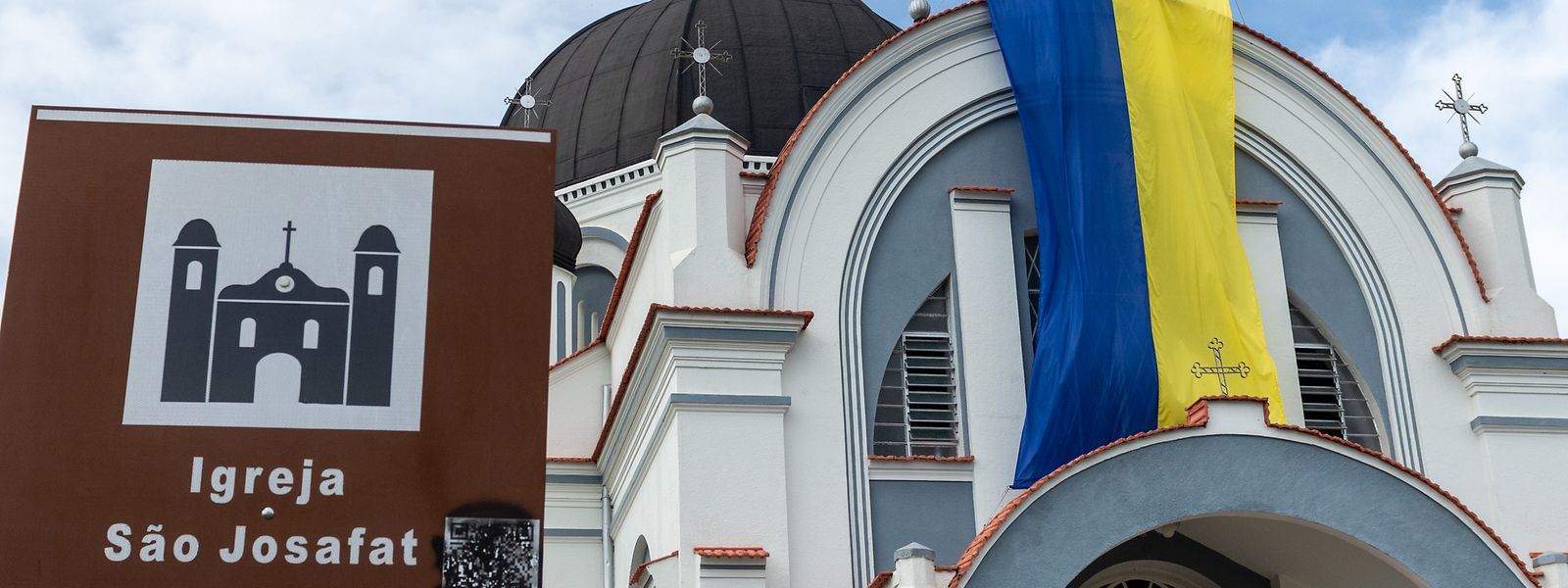 Eine Flagge der Ukraine hängt an der Kirche „Sao Josafat“ neben einem Schild mit dem Namen der Kirche auf Portugiesisch. Weil Prudentopolis abgelegen und die Religiosität stark ist, haben sich Kultur und Sprache der Migranten aus der Ukraine gehalten.