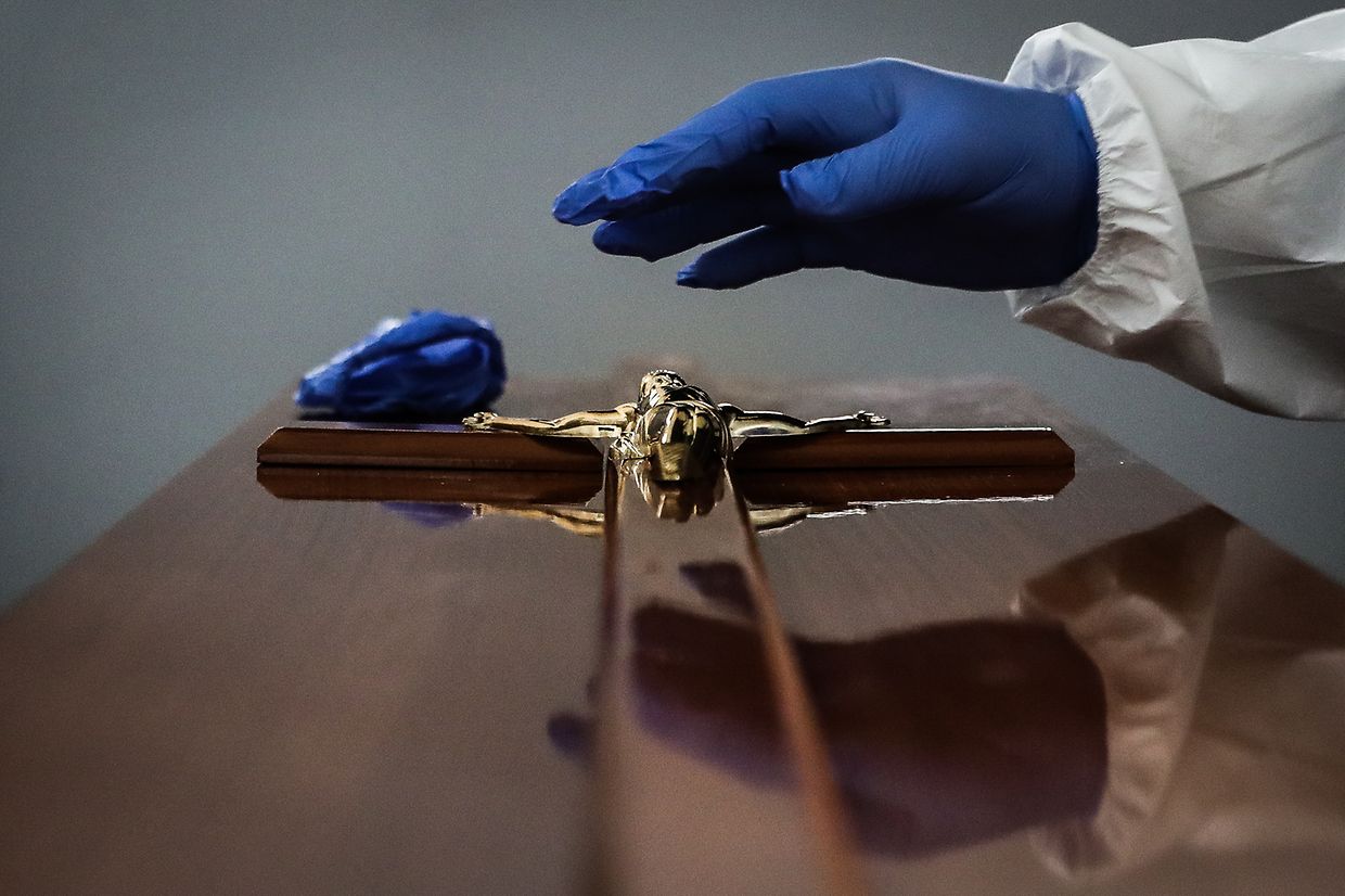 Um funcionário coloca uma imagem de Jesus Cristo em cima do caixão.