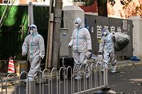 People wearing personal protective equipment (PPE) walk near a residential area under lockdown due to Covid-19 coronavirus restrictions in Beijing on November 26, 2022. (Photo by Noel CELIS / AFP)