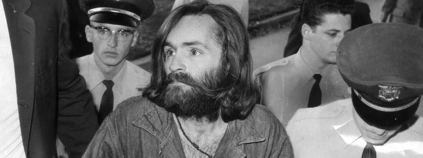 Charles Manson auf dem Weg zu einem Gerichtstermin. Die markante Hakenkreuz-Tätowierung hat er sich zu diesem Zeitpunkt noch nicht zugefügt. 