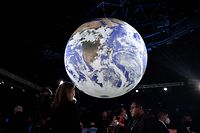 A journalist does an interview under a globe at the World Leaders' Summit of the COP26 UN Climate Change Conference in Glasgow on November 2, 2021. - COP26, running from October 31 to November 12 in Glasgow will be the biggest climate conference since the 2015 Paris summit and is seen as crucial in setting worldwide emission targets to slow global warming, as well as firming up other key commitments (Photo by ALAIN JOCARD / AFP)