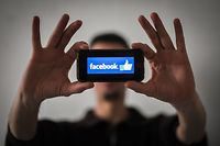 (FILES) In this file photo taken on January 15, 2019 a man holds a smartphone with the logo of social network Facebook in Nantes, western France. - Winning back trust is seen as the key priority for Facebook as the world's biggest social network readies its financial update on the final months of 2018 on January 30, 2019. Facebook is looking to rebound from a horrific year marked by a series of scandals over data protection and privacy, and concerns that it had been manipulated by foreign interests for political purposes. (Photo by LOIC VENANCE / AFP)