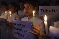 Students hold candles and placards as they pay tribute to the victims of a mass shooting carried out by teenage gunman at an elementary school in Texas, at a school in Amritsar on May 25, 2022.+ (Photo by Narinder NANU / AFP)