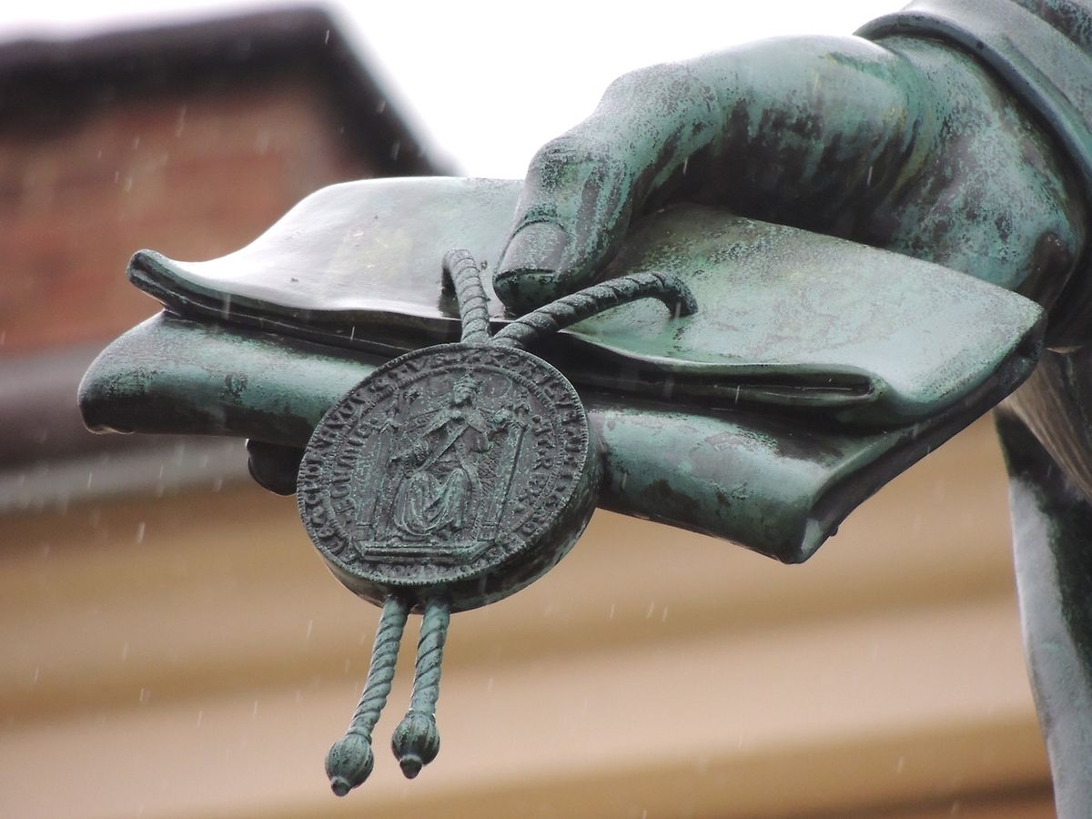Detailansicht des Monumentes von Karl IV. am Fuße der Karlsbrücke: die Gründungsbulle der Prager Universität.